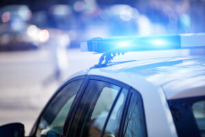 Police car with blue lights on the crime scene in traffic urban environment.