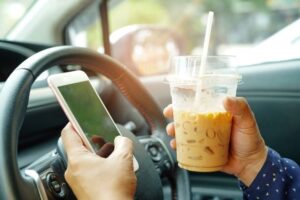 Driving a car while texting and drinking coffee