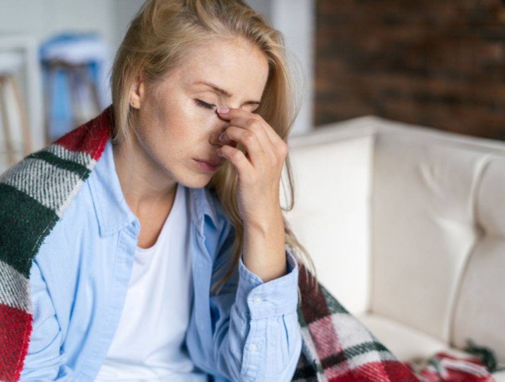 Tired woman with closed eyes touching nose bridge (Loss of Smell: No Longer Telltale Sign of COVID)