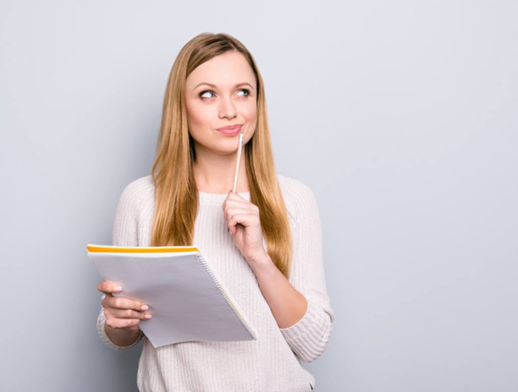 girl having copybook and pen in hands looking up,