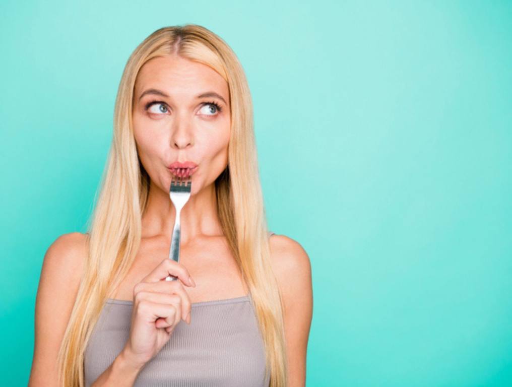 Woman holding in hand kitchen ware licking fork (Go-To Meals for Adults Who Eat Like Children)