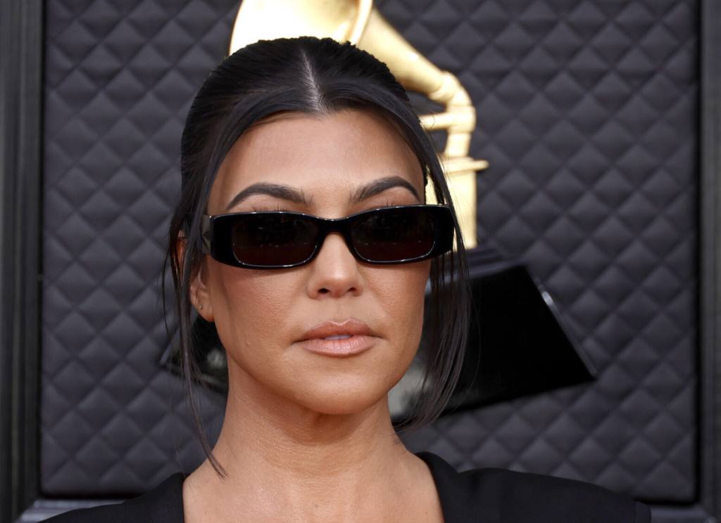 Kourtney Kardashian attends the 64th Annual GRAMMY Awards wearing sunglasses and a black top with her hair parted in the middle.