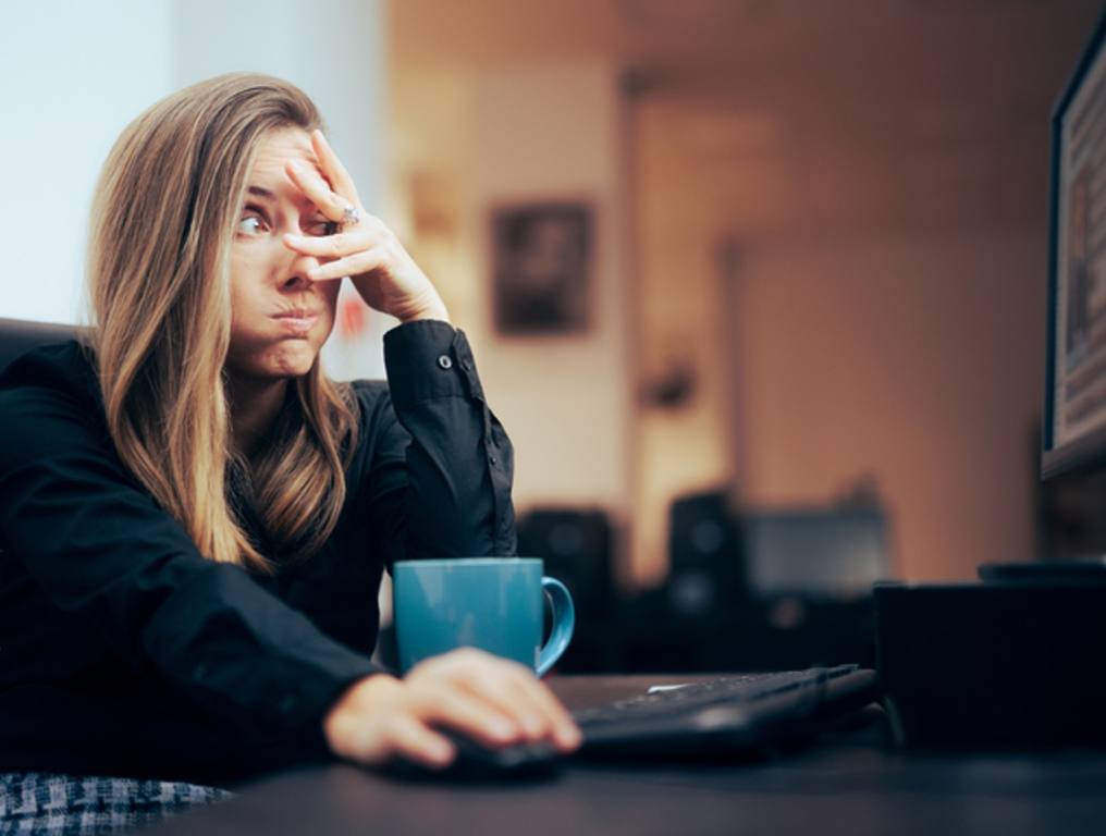 Woman Covering Her Eyes while Browsing the Internet at office, office behaviors concept