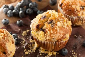 Homemade Blueberry Muffins on a table with blueberries in the background