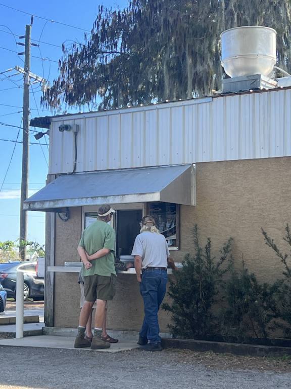 Two men standing outside of a nondescript window of a tan and white building