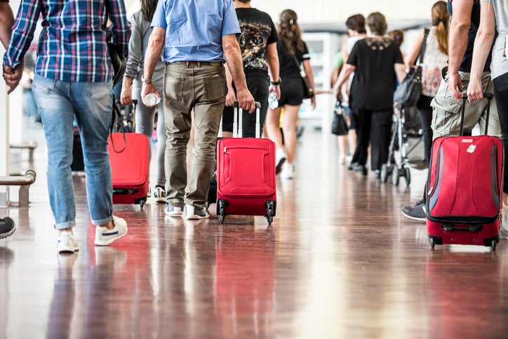 Travelers with suitcases walking through the airport. airport travel hacks