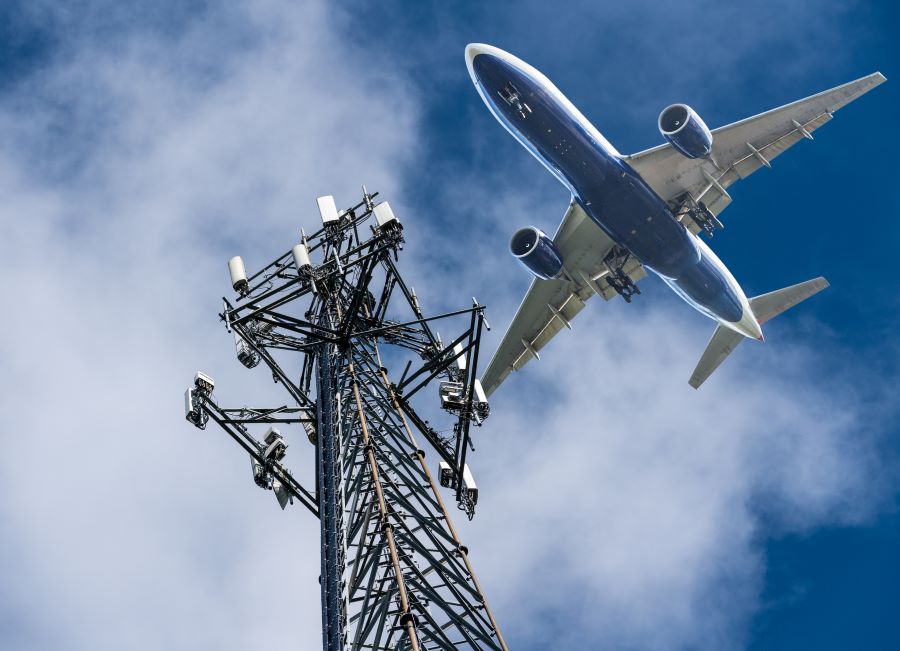 View of a plane flying overhead near a communications tower for Deals On Flights From Fort Myers