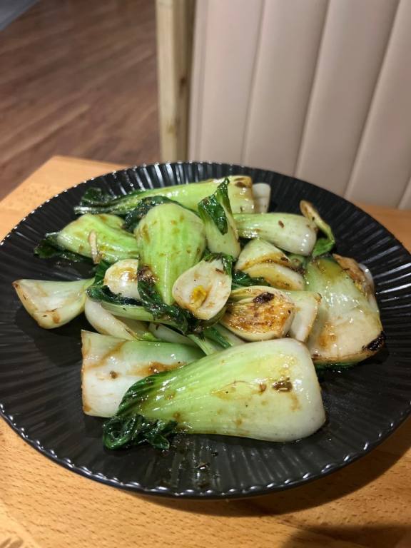 A round black plate filled with bulbs of green bok choy.