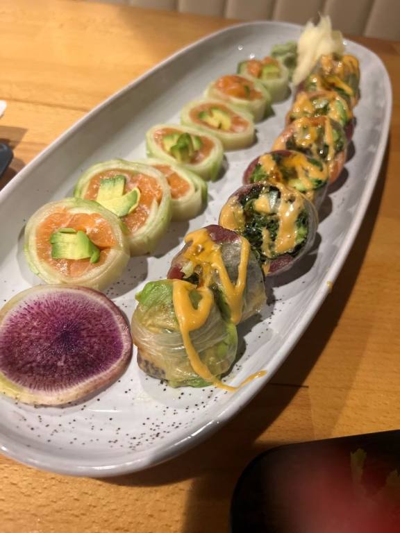 A white plate lined with two different kinds of sushi rolls