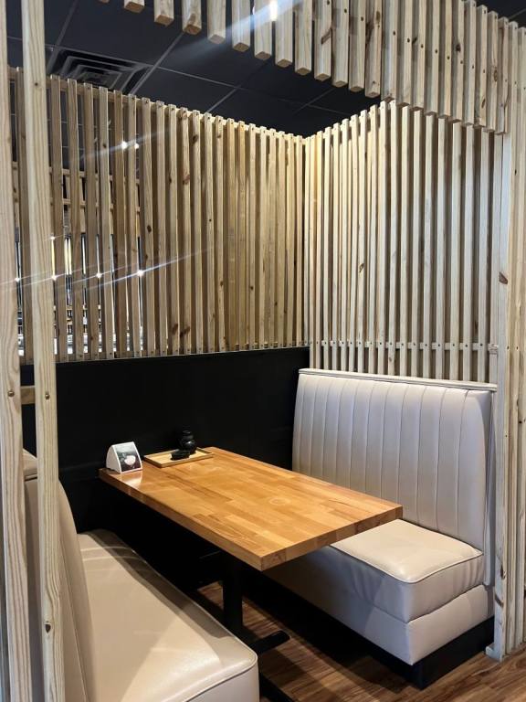 private looking booth with white leather cushioned seats and light wooden table