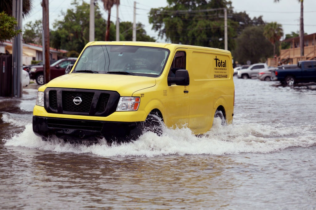 A vehicle drives through a flooded street on June 13, 2024, in Hallandale Beach, Florida. Tropical moisture passing through the area has caused flooding due to the heavy rain. Forecasts are calling for more rain in an area already saturated with water.