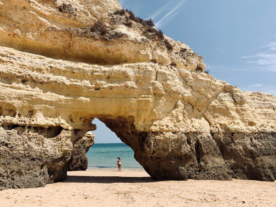 dreamy beaches with arched rock formation and water in background