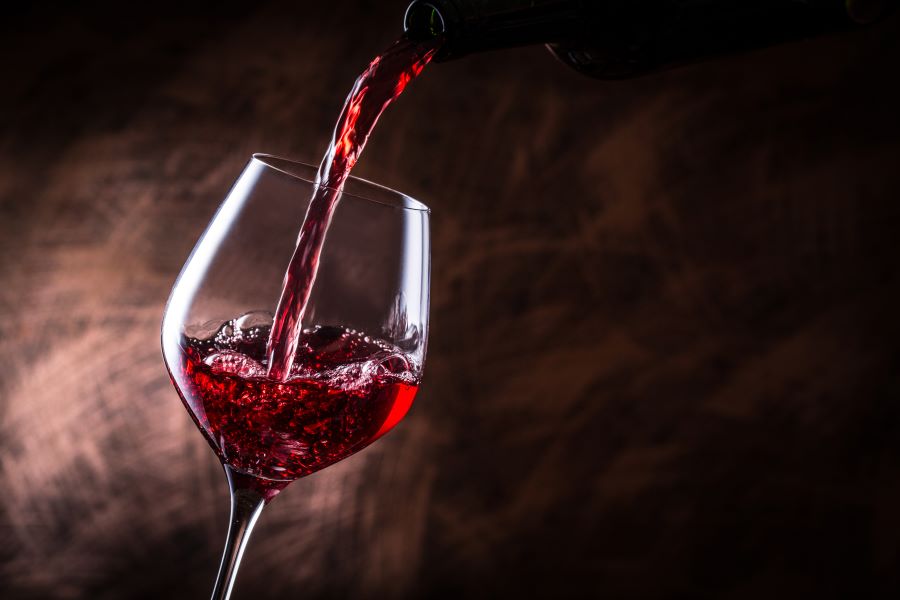 tilted wine glass with red wine being poured into it for wine for Father's Day