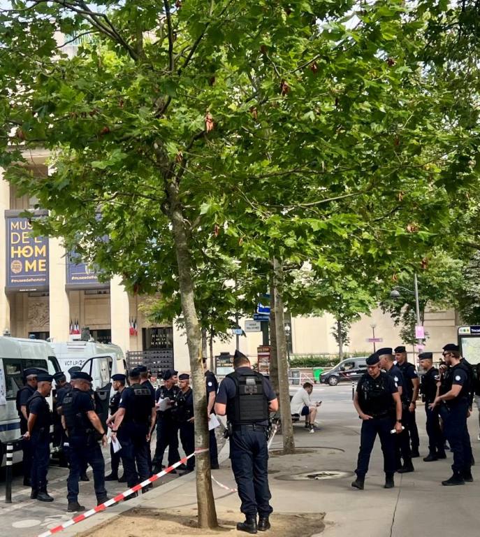 Large gathering of police offers on a city street, under a tree.