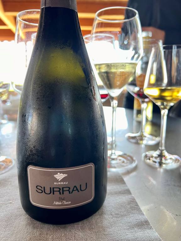 Bottle of Surrau Sparkling Wine with full wine glasses n the background