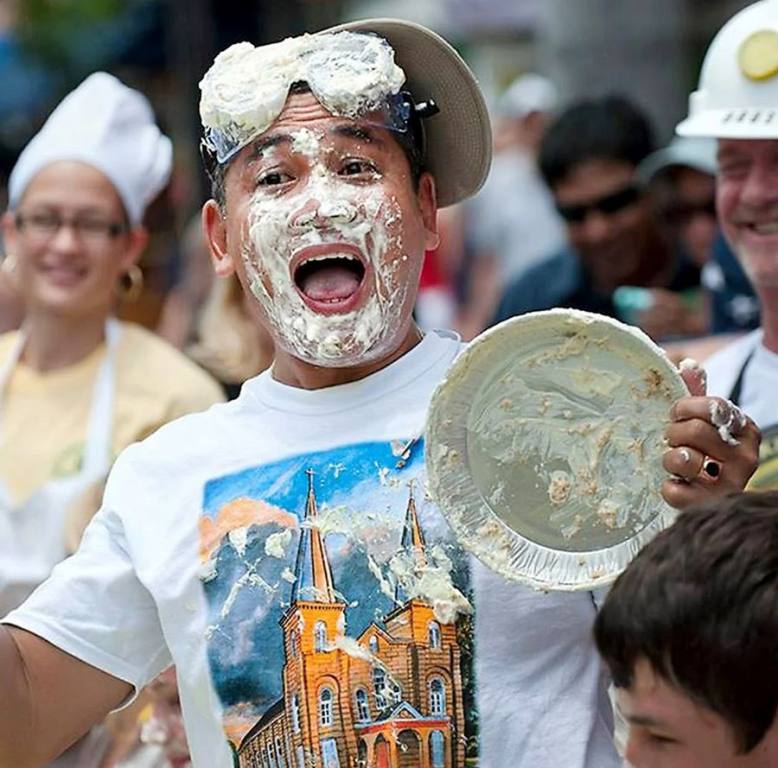 Man with face covered in pie and holding an empty pie tin