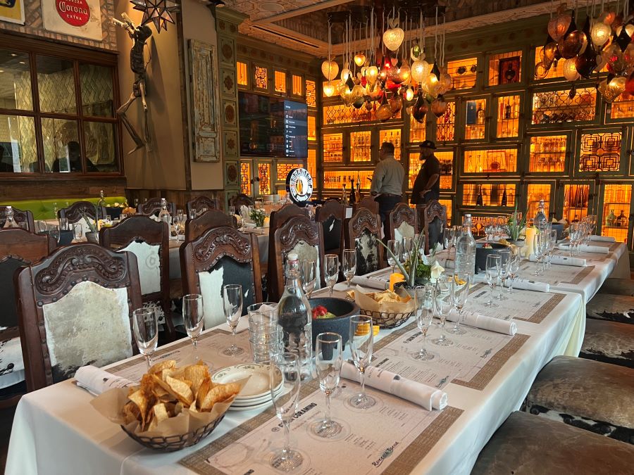 Long table, set with wine glasses, dishes and bowls of tortilla chips for Kevin Hart Tequila Dinner In Naples