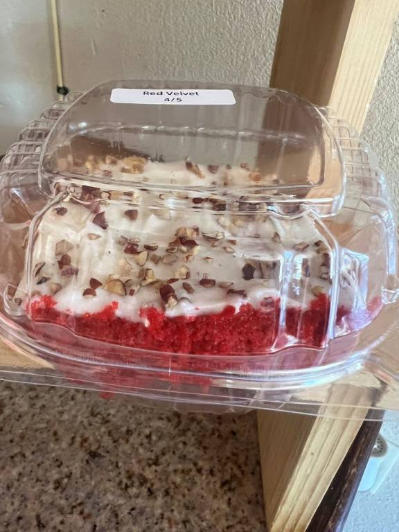 Piece of red velvet cake in a see through plastic to-go container