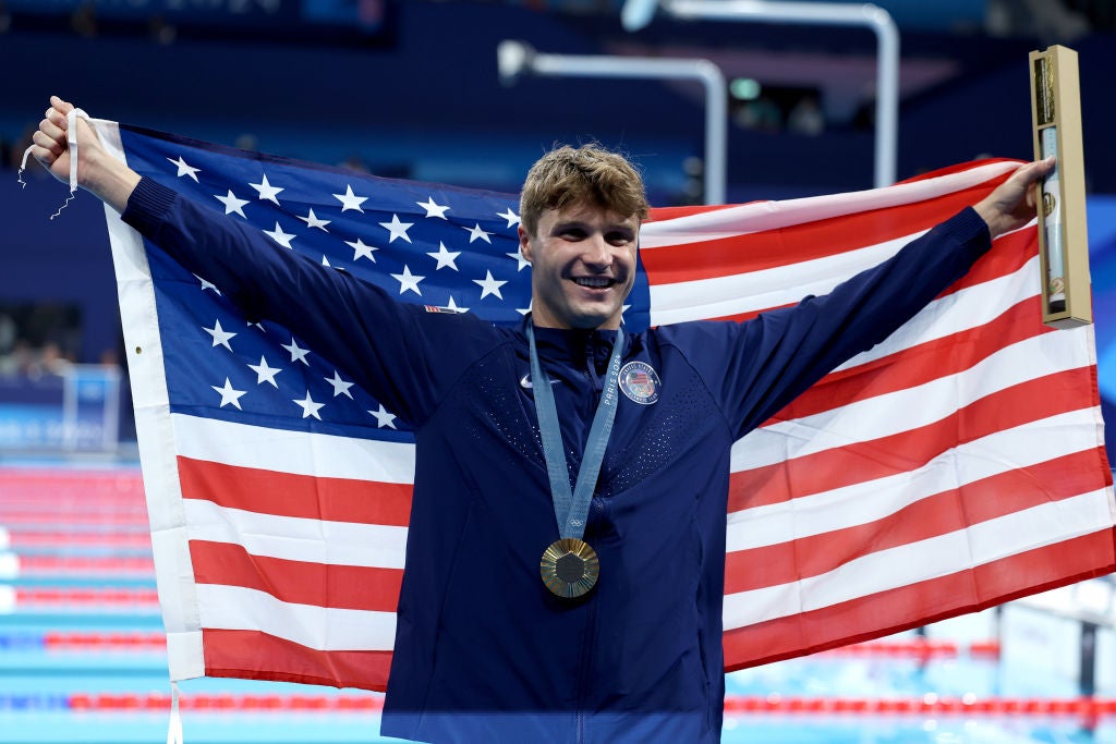 World record setting Gold Medalist Bobby Finke of Team United States poses with the national flag of the United States following the Swimming medal ceremony after the Men's 1500m Freestyle Final on day nine of the Olympic Games Paris 2024 at Paris La Defense Arena on August 04, 2024 in Nanterre, France.