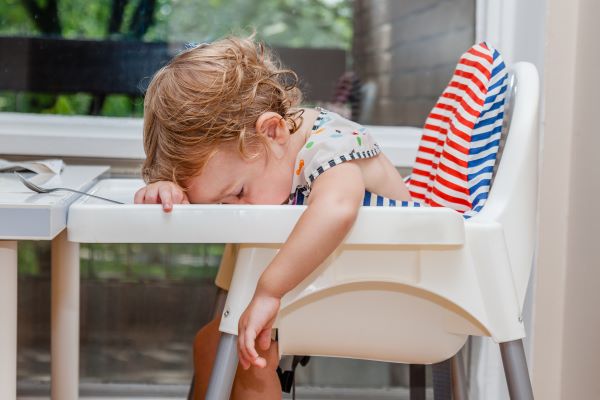 Tired child sleeping in highchair after the lunch. Baby over eating and fall asleep just after feeding lying his face on the table tray, part of baby videos to brighten your day