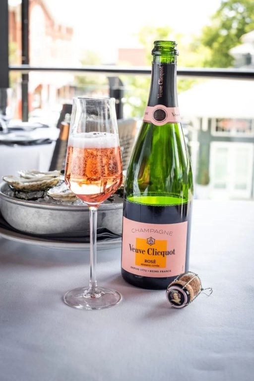 Bottle and glass of Veuve clicquiot Rose Champgne part of the Oyster Specials In Downtown Naples