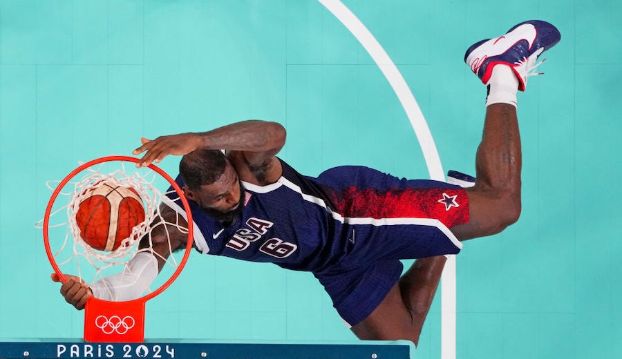 A look from above a basketball hoop as Lebron James dunks a ball, his legs flying to a near horizontal position. It's one of the 5 Top Olympic Moments From The Summer Games