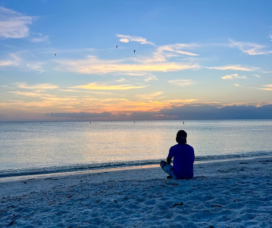 msn sitting by himself on the beach at sunset in Bonita spings at top in most expensive places to retire