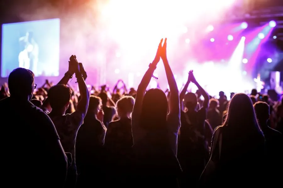 a big crowd at a concert, dozens of hands are in the air as Florida is the number 1 most fun state