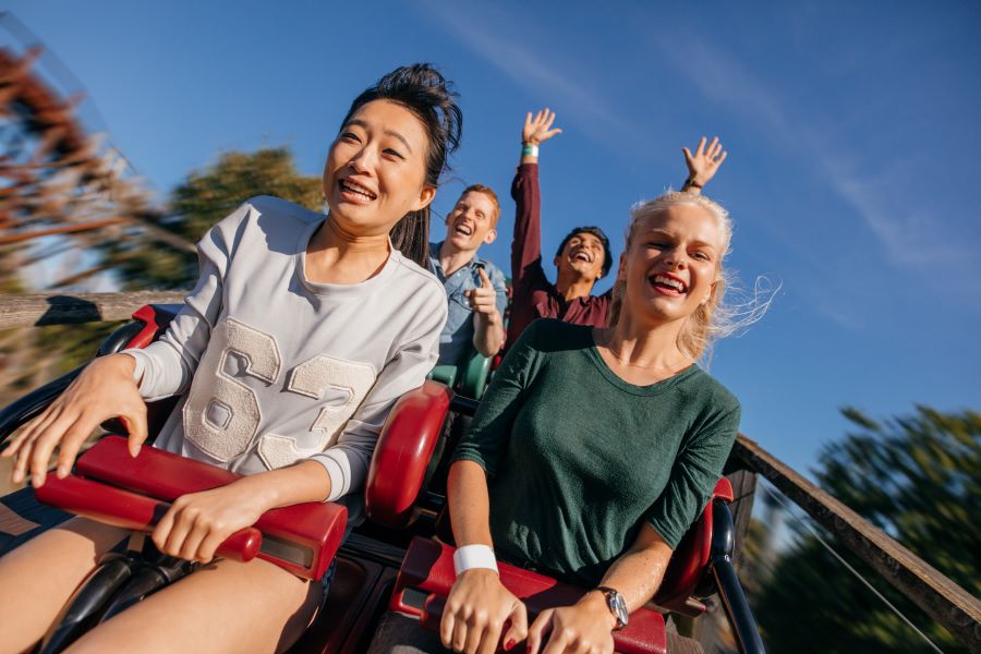 Two girls in the front of a rollercoaster cart smiling as Florida is the number 1 most fun state in America