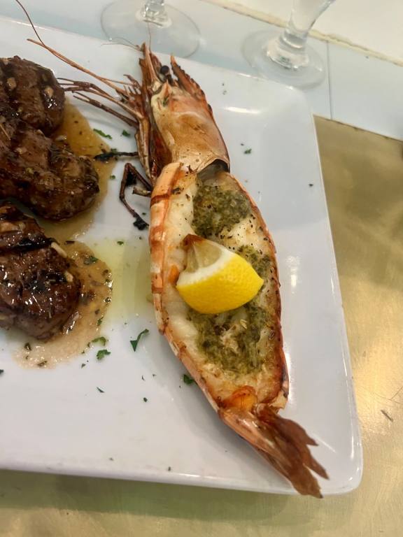 one big prawn cut in half, cooked and topped with herbs and a lemon wedge.