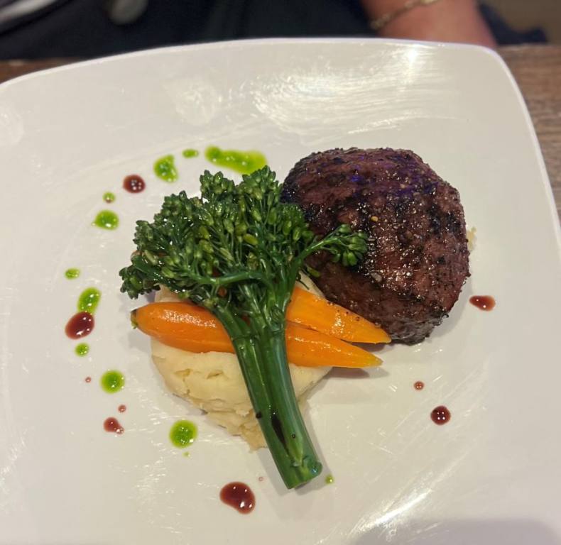 White plate with a round cut steak filet, stalk of broccoli and scoop of mashed potatoes