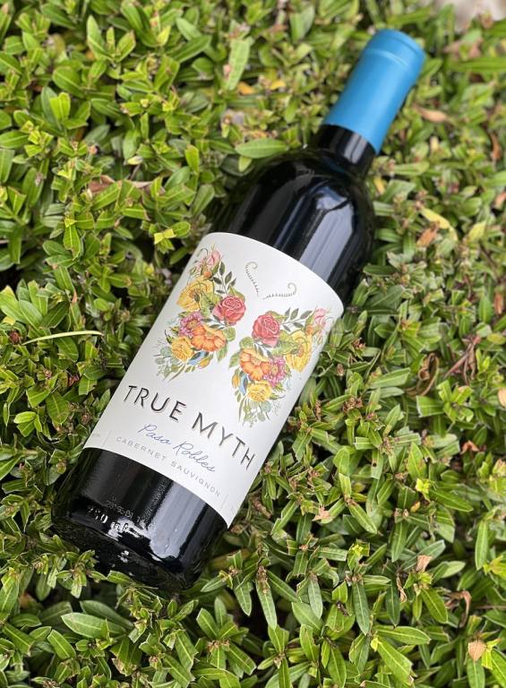 Bottle of True Myth cabernet with a green bush in background