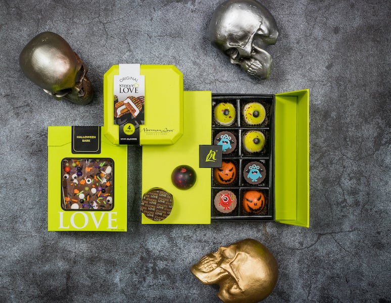 Norman Love Halloween chocolates with several boxes of candy and fake skulls skattered around