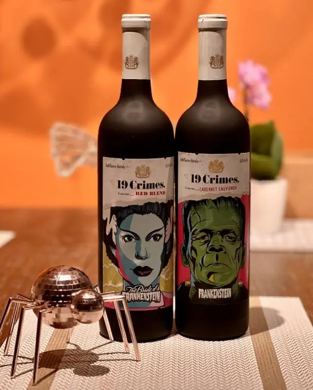 19 Crimes Frankenstein and Bride of Frankenstein wine bottles on a table with an orange background for Halloween Themed Wines