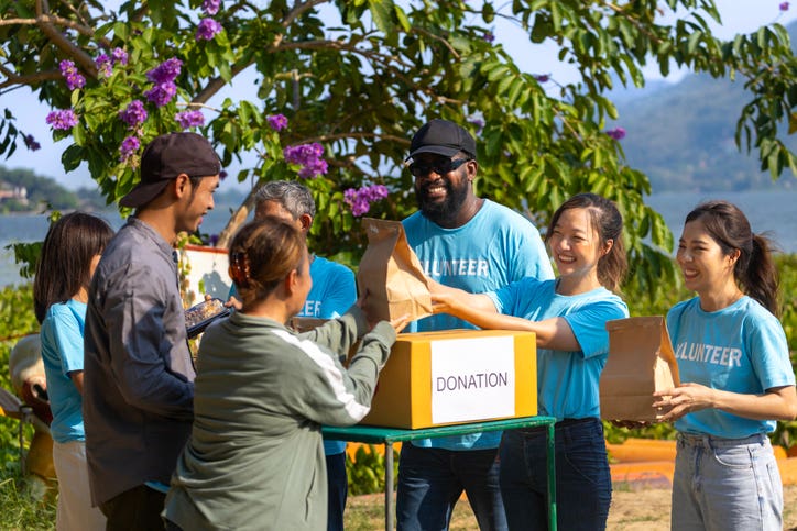 Team of humanitarian aid volunteer is distributing basics survival kit relief bag to the homeless and refugee people in the conflict area to help solving poverty and spreading kindness