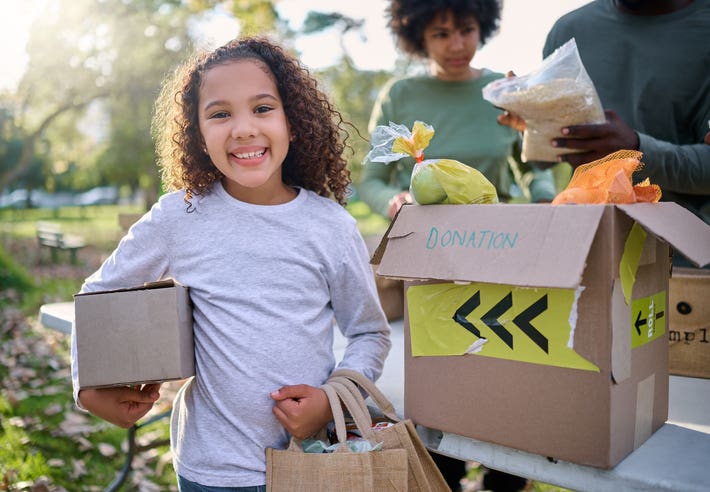 Food, donation and portrait of child in park with smile and grocery box, healthy diet at refugee feeding project. Girl, charity and donations help feed children and support from farm volunteer at ngo