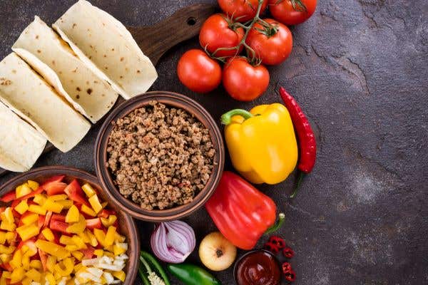 bowl of brown rice surrounded by tomatoes, red and yellow peppers, garlic bulbs, rolled tortillas for what florida vegan restaurants serve