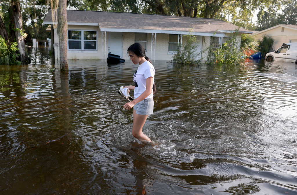 A person walks through a flooded road after Hurricane Helene hit the area as it passed offshore on September 27, 2024 in Crystal River, Florida. Hurricane Helene made landfall Thursday night in Florida's Big Bend with winds up to 140 mph and storm surges. 