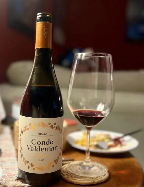 Bottle of Conde Valdemar Reserva Rioja on a dinner table with plates a full glass of wine