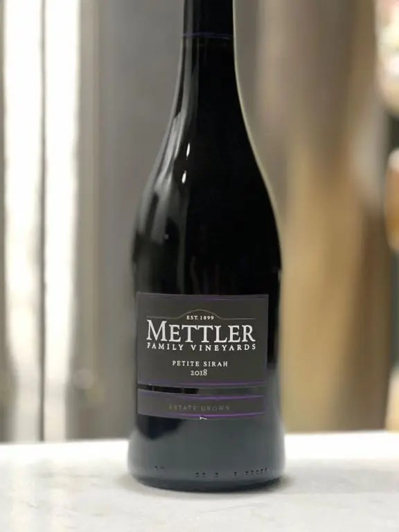 Bottle of Mettle Petite Sirah against a brushed metal refreigerator